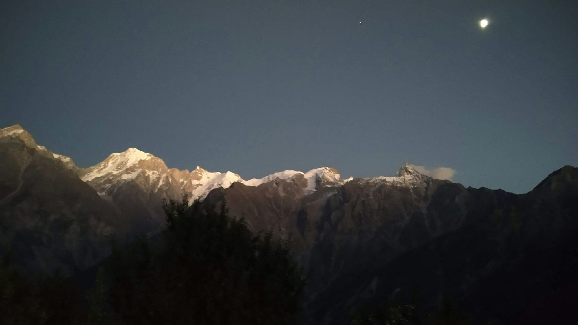 A moon over mountain peaks